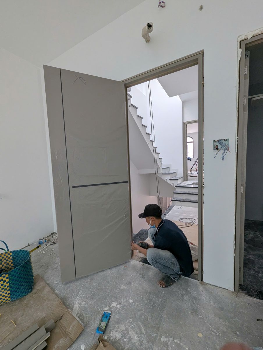 nhân viên kỹ thuật đang tiến hành lắp đặt cửa cẩn thận, chắc chắn